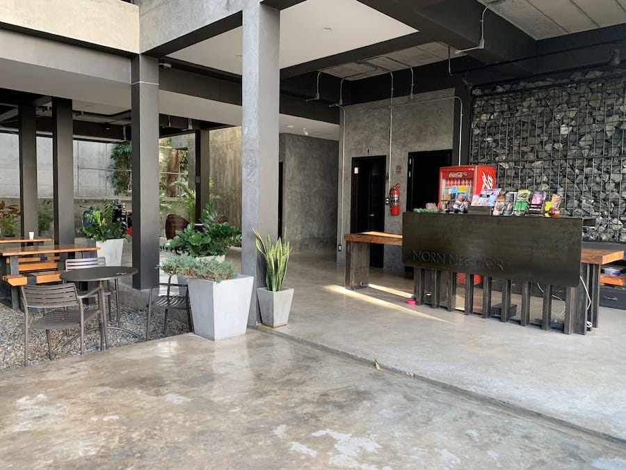 Spazio interno moderno con pilastri in cemento, zone relax e una parete in pietra.