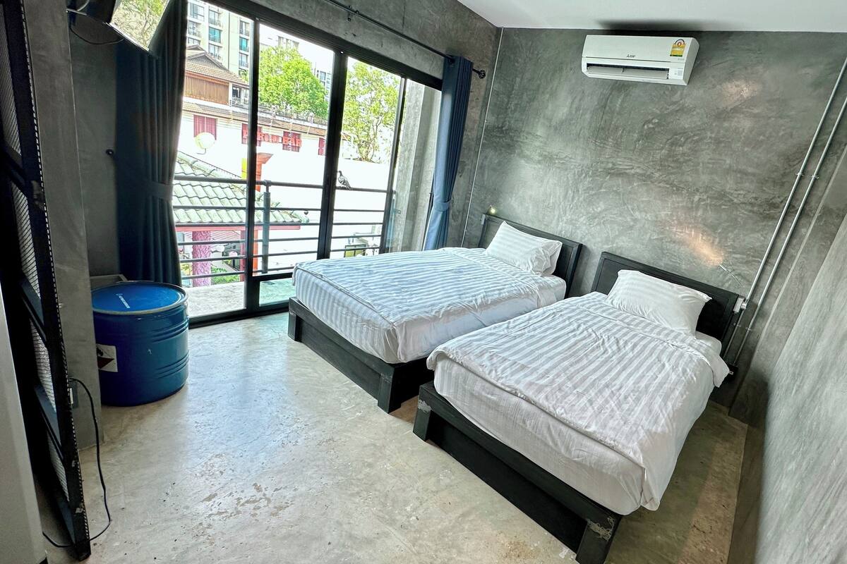 Une chambre d’hôtel moderne avec deux lits, une grande fenêtre et un appareil de climatisation.