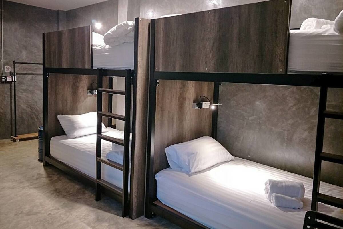 Une chambre avec un lit superposé, une échelle, une petite table et un luminaire fixé au mur.