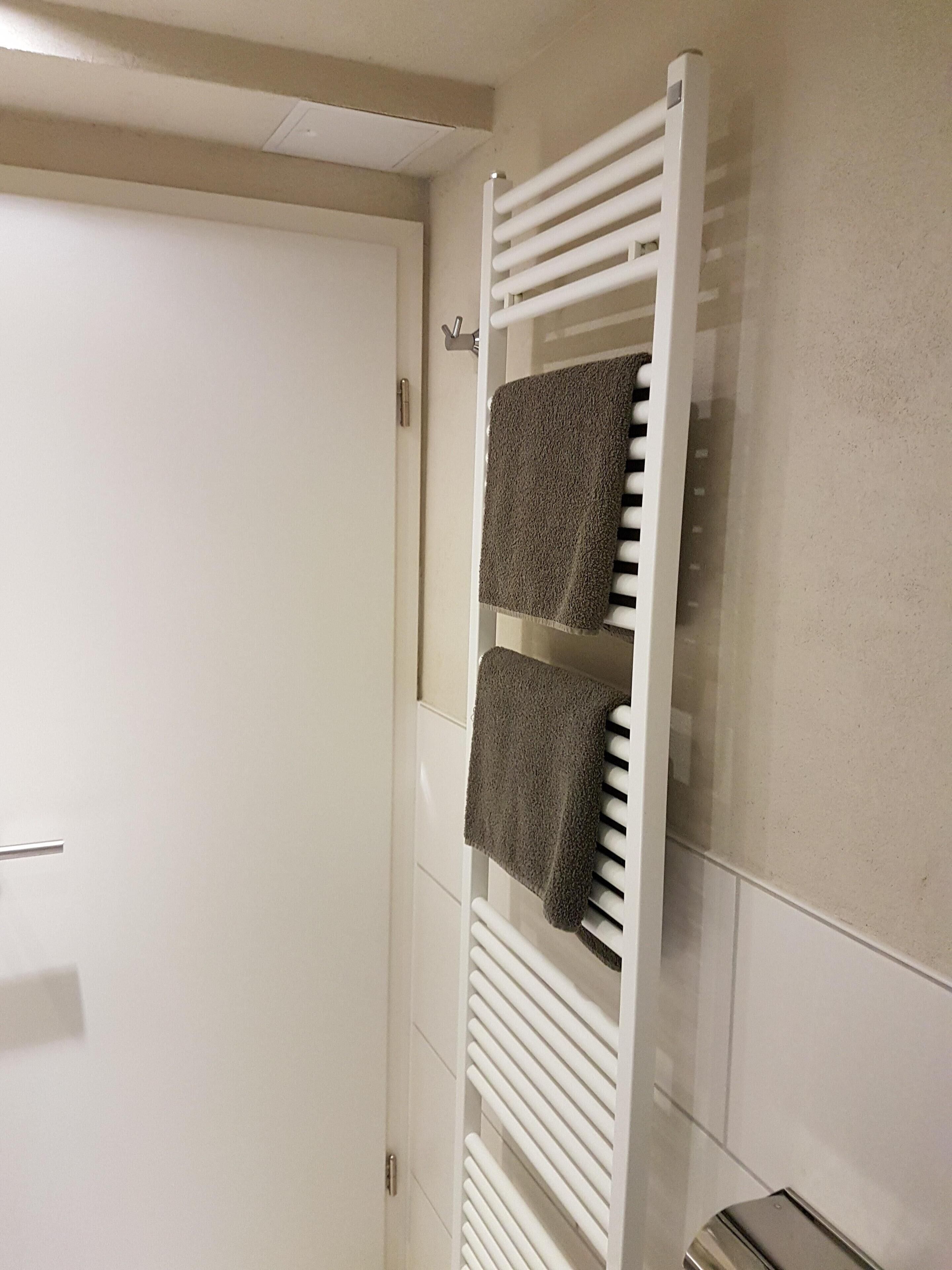 Un bagno con un portasciugamani bianco che contiene due asciugamani.