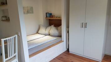 A bedroom with a built-in bed, a wardrobe, and a small shelf with books.