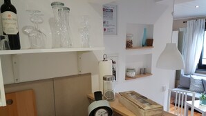 Une cuisine moderne avec une machine à café, une bouteille de vin et des verres disposés sur des étagères.