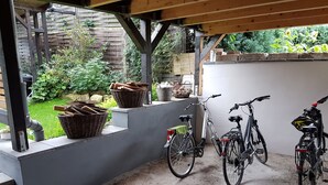 Un espace extérieur abrité, doté d’un sol en béton, d’un banc en bois et d’un support à vélos pouvant accueillir deux vélos.