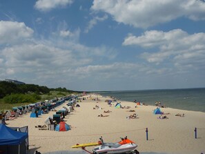 Una playa con hileras de sillas y sombrillas, un jet ski y una carpa.