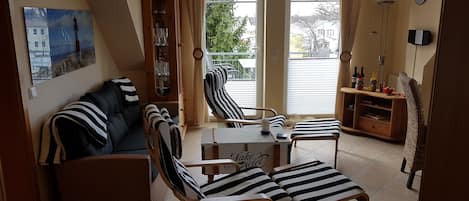 A cozy living room with a sofa, striped chairs, a small table, and a bookshelf.