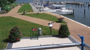 Un puerto deportivo con barcos amarrados, un sendero cubierto de césped y una bandera.