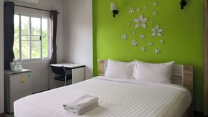 A hotel room with a bed, a desk, and a window.