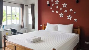 Hotelkamer met een groot bed, een bureau met stoel, een airconditioning en een raam met gordijnen.