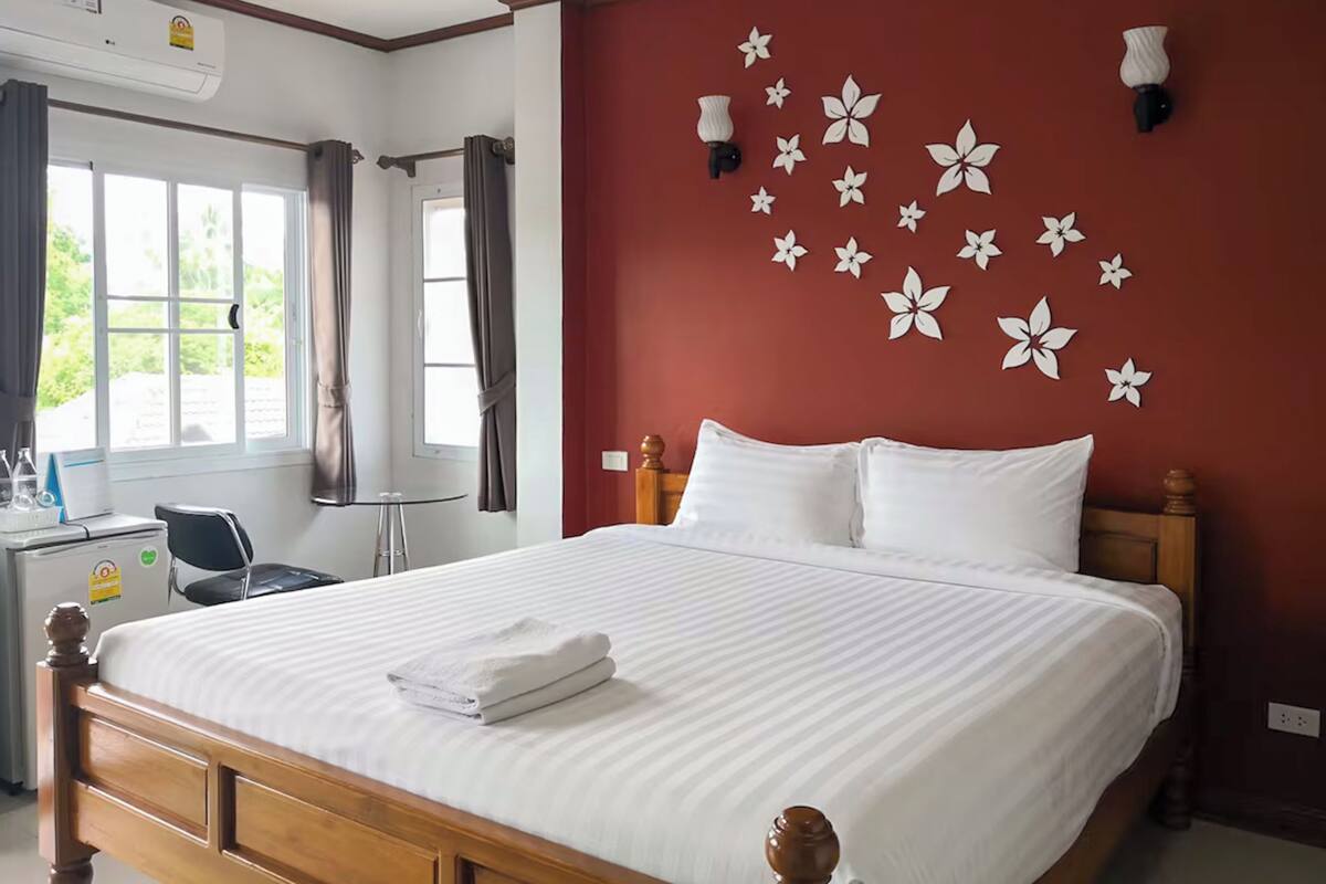 Une chambre d’hôtel avec un grand lit, un bureau avec une chaise, un appareil de climatisation et une fenêtre avec des rideaux.