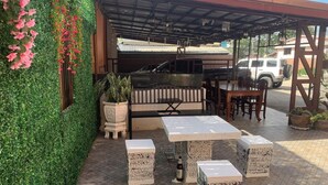 An outdoor patio area with a barbecue grill, seating, and potted plants.