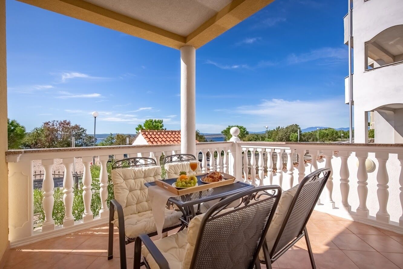 A balcony with a table set for two, featuring a meal tray and a drink.