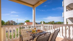 A balcony with a table set for two, featuring a meal tray and a drink.