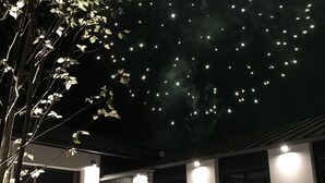 A modern building with a covered outdoor area, illuminated by string lights and a central light fixture. - Yufuin Rikka (Yufu)