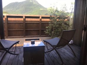 Un área de estar al aire libre con dos sillas, una mesa, un cerco de madera y vistas a la montaña.