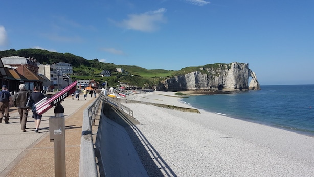 A coastal promenade with a pebble beach, a promenade with a railing, and white cliffs in the background. -  Quiet 3* Cottage 10m from Étretat | Fenced Garden | Dogs Welcome  Farm animals (Criquetot L Esneval)