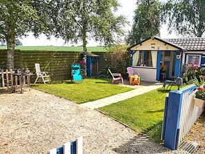 A fenced backyard with a lawn, a small shed, and a blue and yellow building with a window.