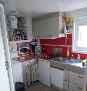 A compact kitchen with white cabinets, a microwave, a coffee maker, and a sink.