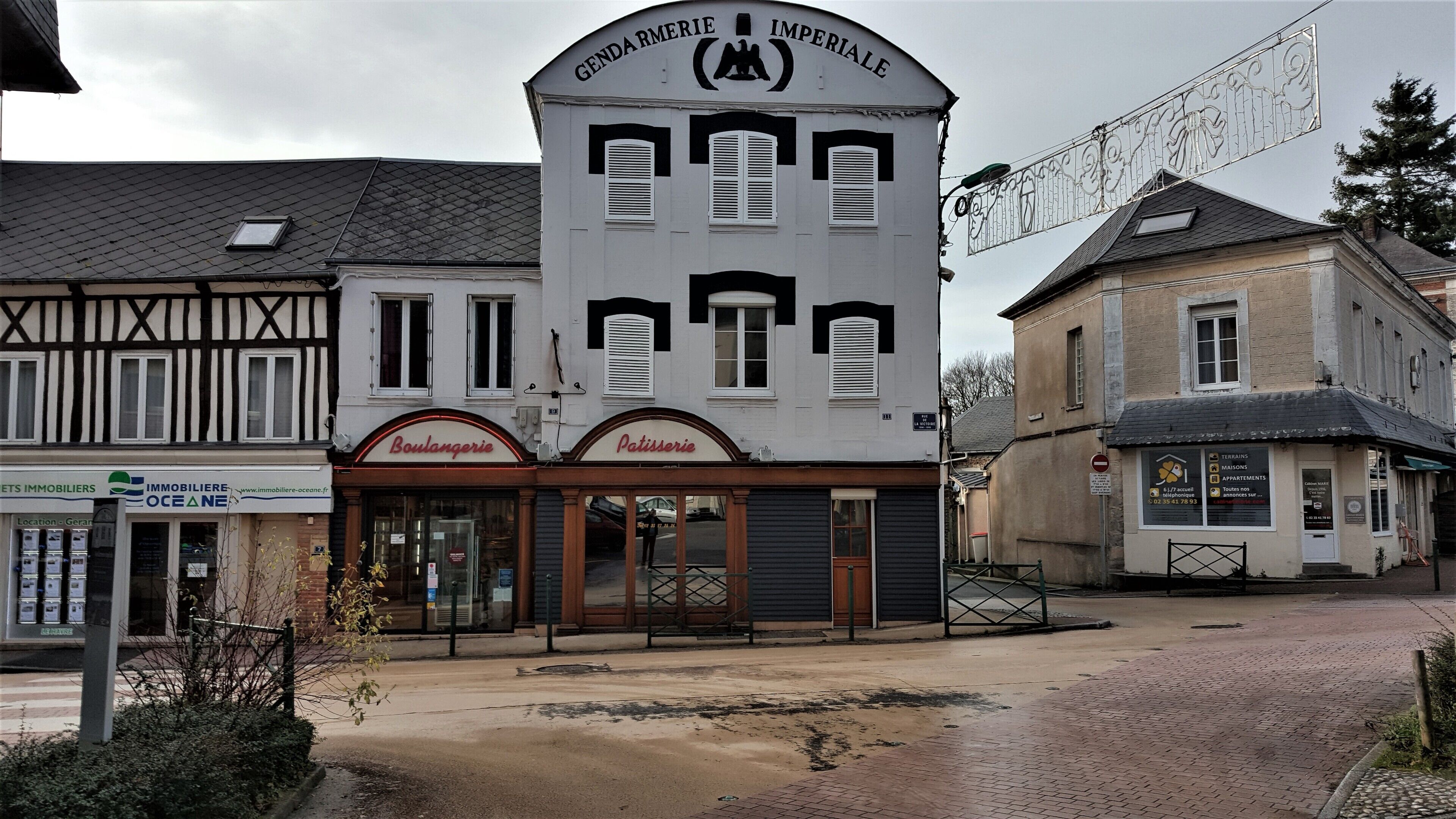 Ein Gebäude mit einem Schild für 'GENDARMERIE IMPERIALE' und einer 'Boulangerie' sowie 'Patisserie' im Erdgeschoss.