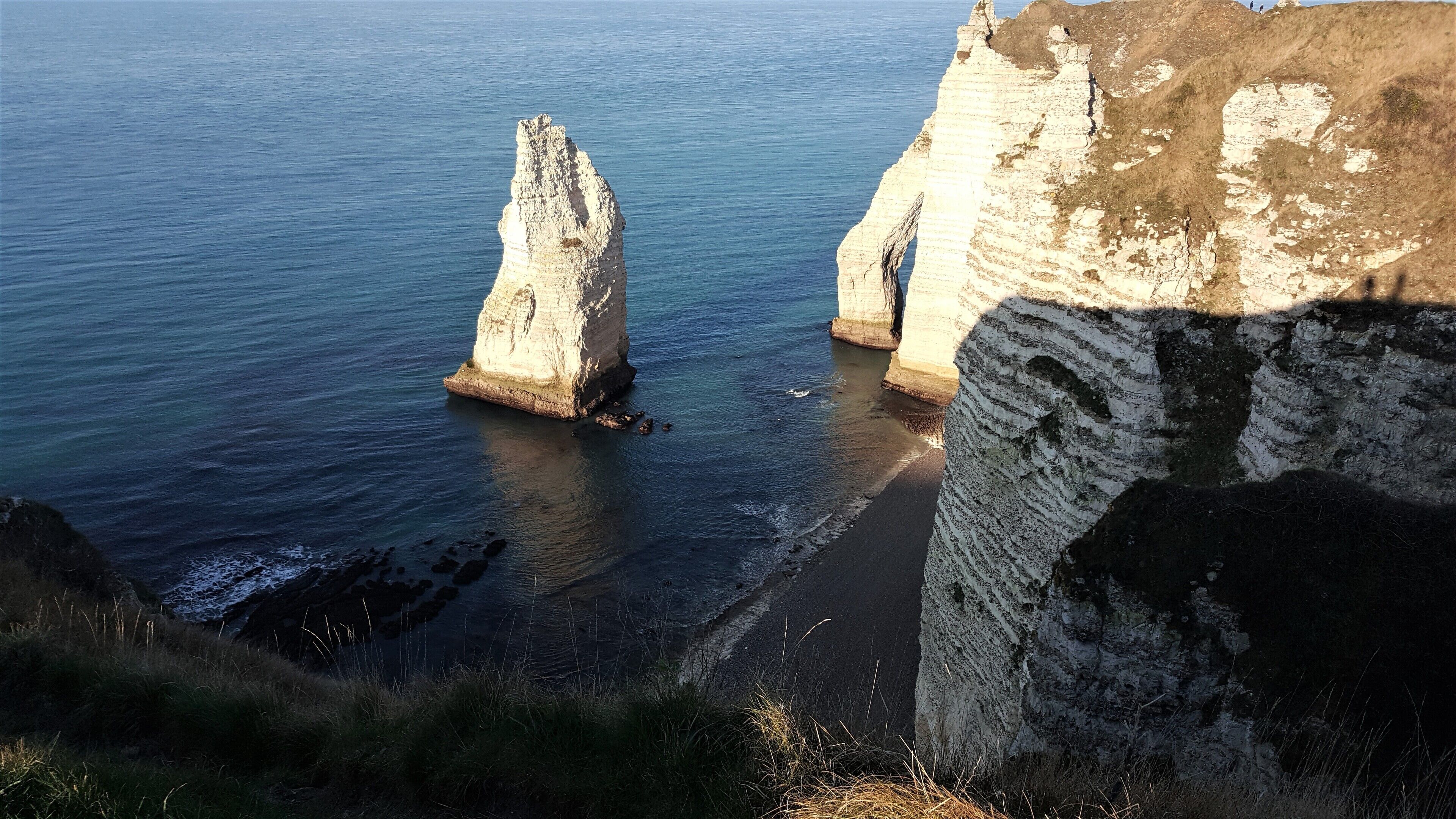 A coastal landscape with prominent white cliffs and a sandy beach.