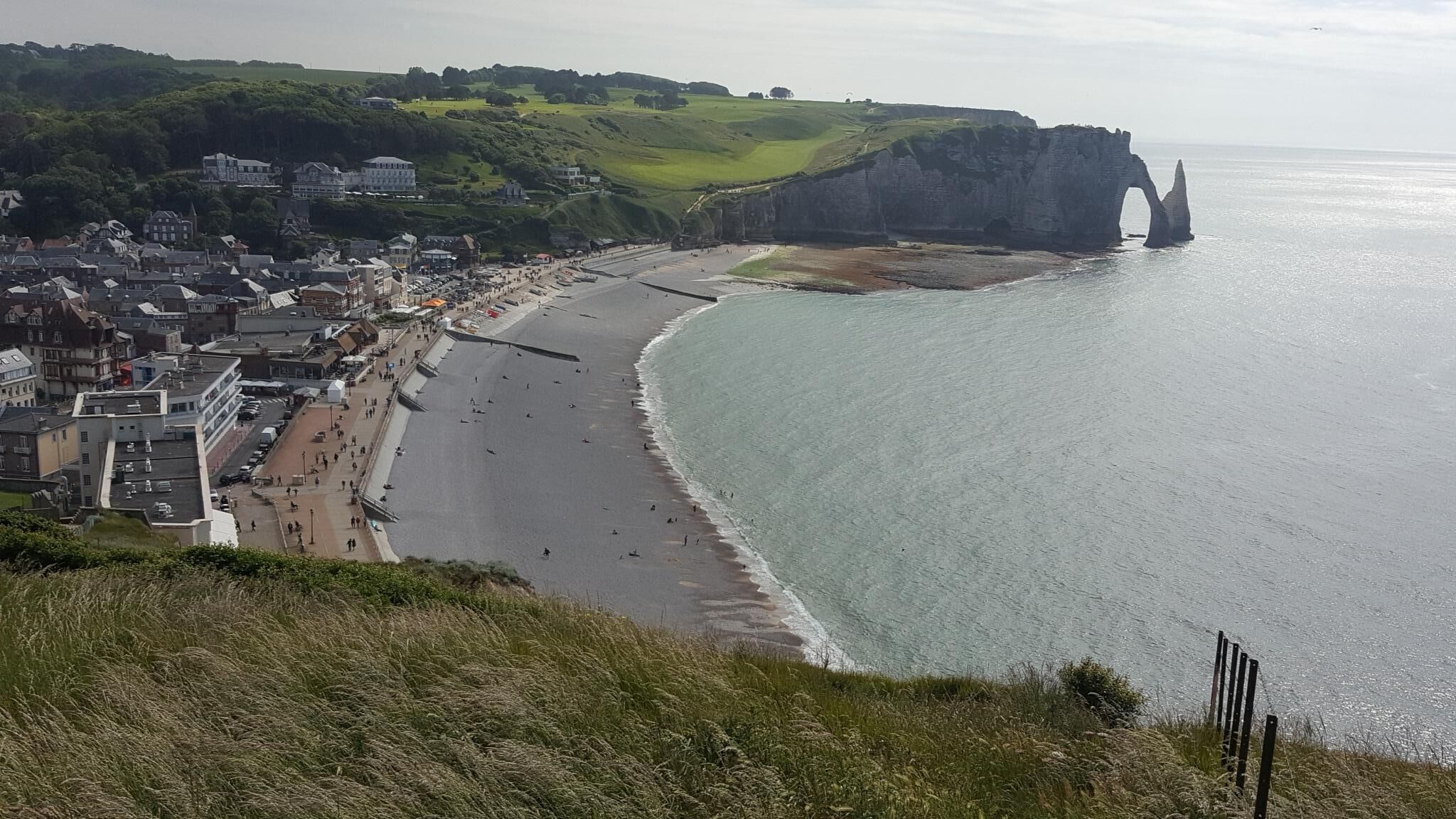Une ville côtière dotée d’une longue plage de sable, d’une falaise percée d’une arche naturelle et de bâtiments qui bordent le rivage.