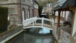 A narrow canal with a white bridge, stone buildings, and a wooden dock. -  Quiet 3* Cottage 10m from Étretat | Fenced Garden | Dogs Welcome  Farm animals (Criquetot L Esneval)