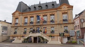 A historic building with a central staircase, multiple windows, and flags.