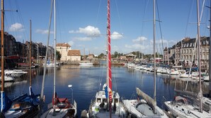 A marina with multiple sailboats docked, a prominent red mast, and historic buildings in the background. -  Quiet 3* Cottage 10m from Étretat | Fenced Garden | Dogs Welcome  Farm animals (Criquetot L Esneval)
