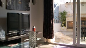 A living room with a flat-screen TV, a glass vase, and a cityscape poster on the wall.