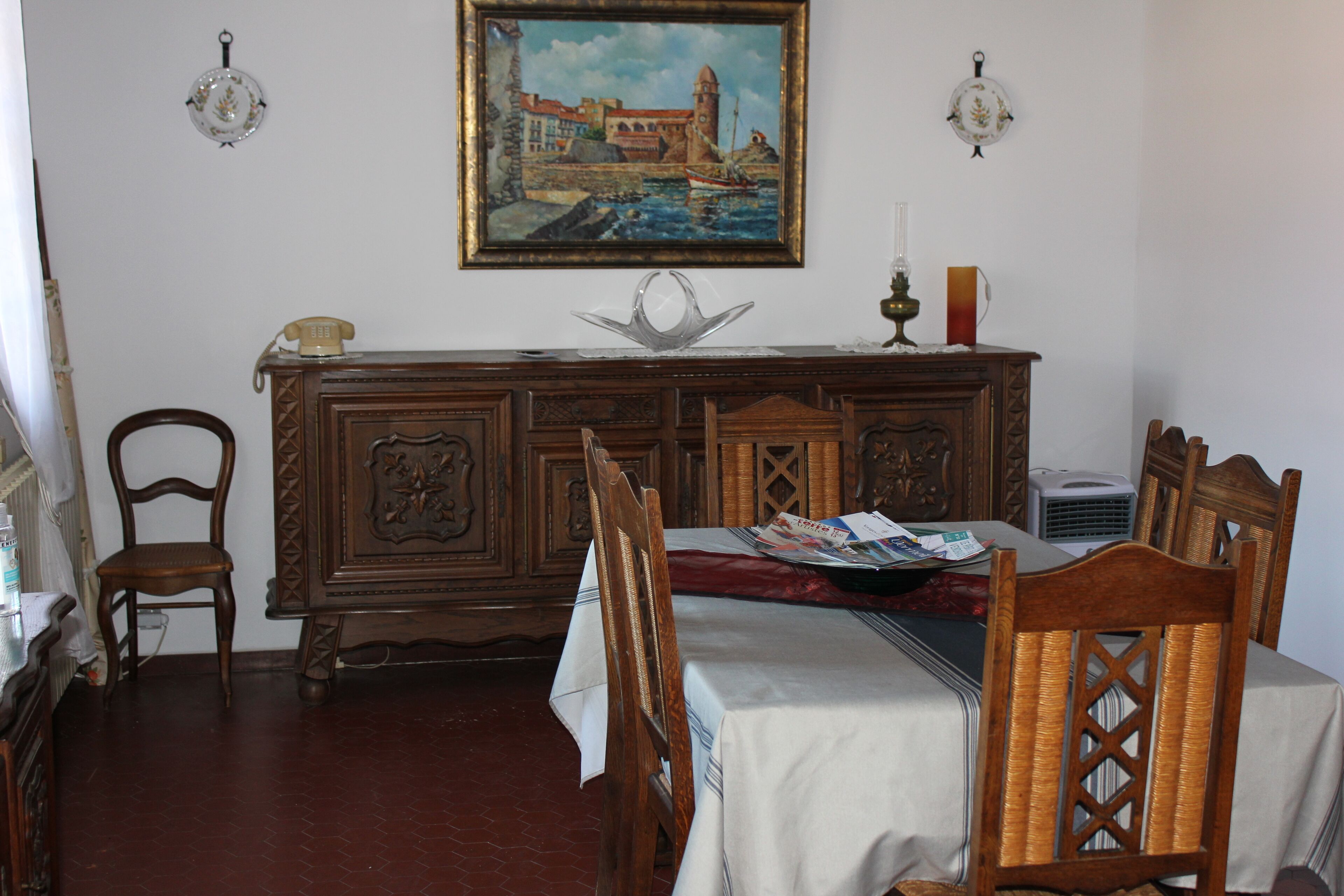 Un comedor con una mesa de madera preparada para dos, un teléfono antiguo y un centro de mesa decorativo.