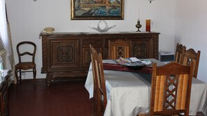 Un comedor con una mesa de madera preparada para dos, un teléfono antiguo y un centro de mesa decorativo.