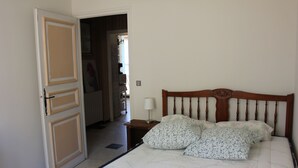 Un dormitorio con cama, mesita de noche y una puerta que da a otra habitación.
