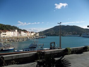 Un port amb vaixells, un passeig marítim i edificis al llarg de la riba.