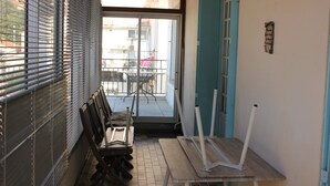 Un pasillo con un banco, una mesa y una puerta que da a un espacio exterior con mesa y sillas.