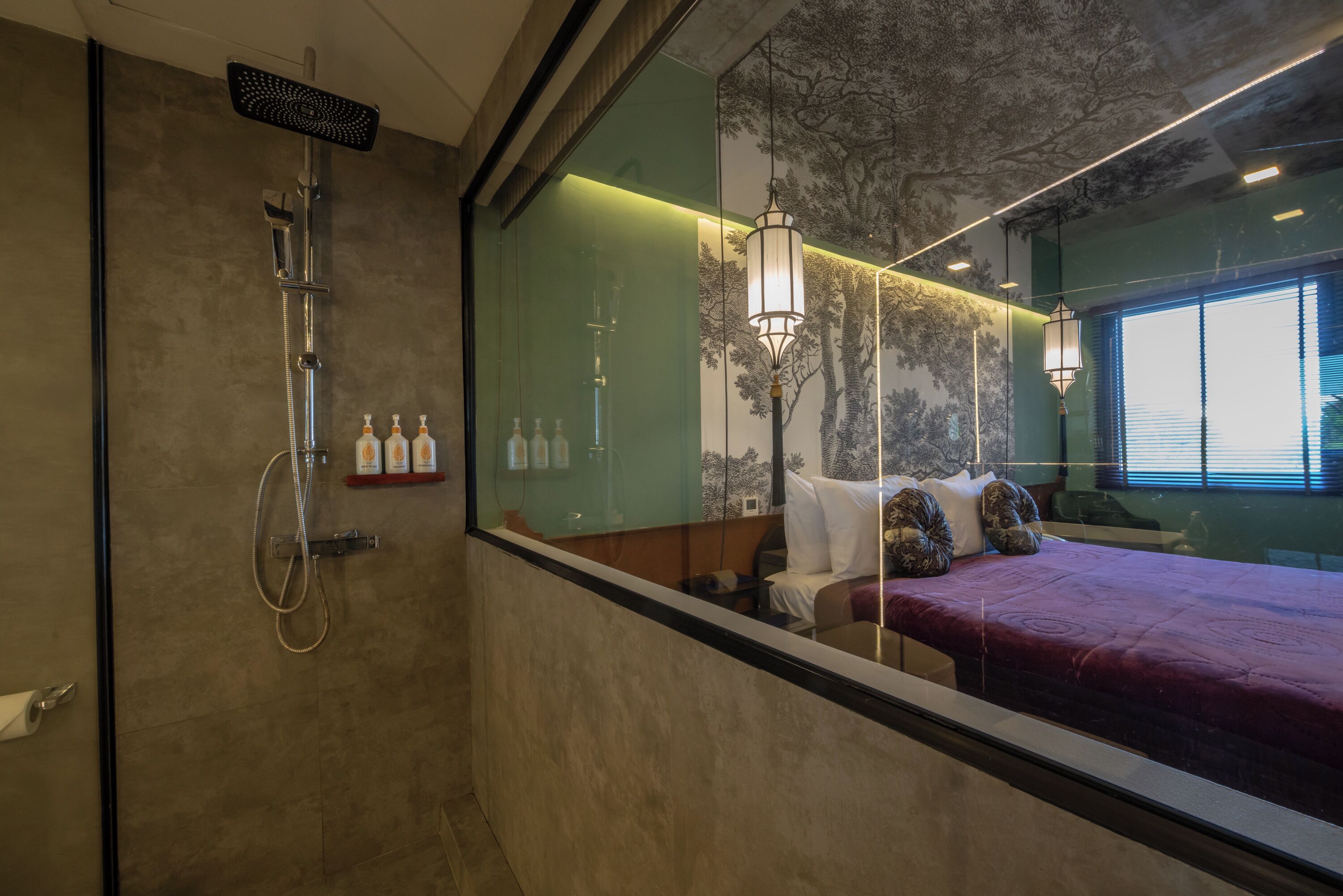 A modern bathroom with a shower, a large mirror, and a bed with a red bedspread.
