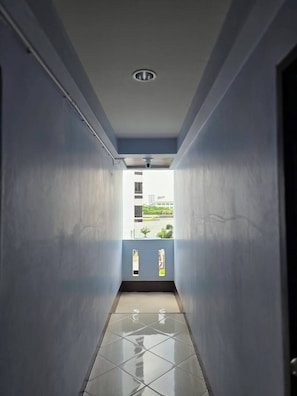 A narrow hallway with a tiled floor and a view of a building outside. - Bella Bella River View (Bangkok)