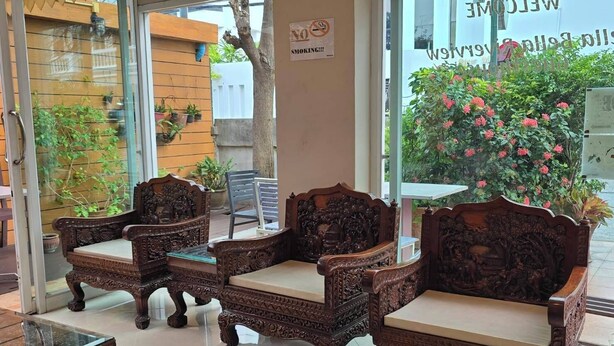 A reception area with ornate wooden chairs, a glass coffee table, and a sign welcoming visitors. - Bella Bella River View (Bangkok)