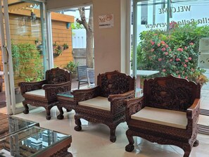 A reception area with ornate wooden chairs, a glass coffee table, and a sign welcoming visitors. - Bella Bella River View (Bangkok)