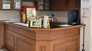 A reception area with a wooden counter, a Coca-Cola refrigerator, a calendar, and a computer monitor. - Bella Bella River View (Bangkok)