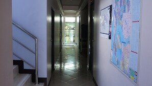 A hallway with a staircase, a map on the wall, and a door leading to another room. - Bella Bella River View (Bangkok)
