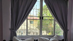 A bed with white linens and two pillows, a window with metal bars, and grey curtains. - Bella Bella River View (Bangkok)