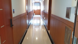A long, well-lit hallway with wooden paneling and a shiny tiled floor, leading to a bright room at the end. - The Beauty Hotel (Gangneung)