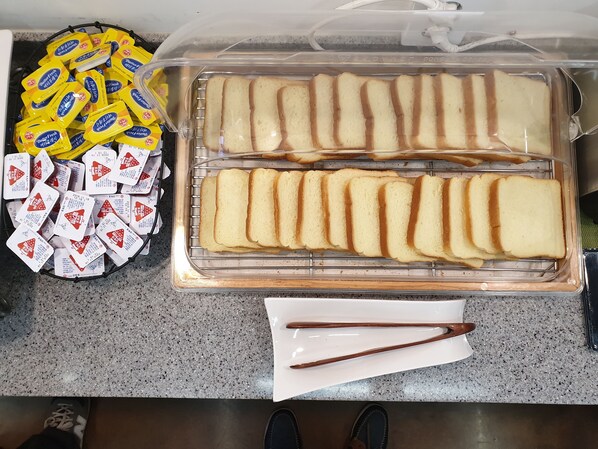 A kitchen counter with a bread display and butter packets. - The Beauty Hotel (Gangneung)