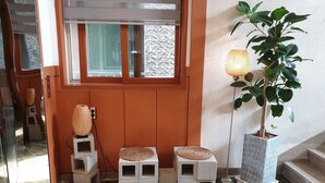 A wooden door with a window, a potted plant, and a floor lamp. - The Beauty Hotel (Gangneung)
