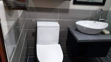A modern bathroom with a white toilet, a sink with a basin, and a mirror above the sink.