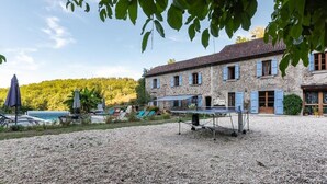 A stone building with a gravel courtyard, outdoor seating, and a pool. - La Souliere (Aubin)