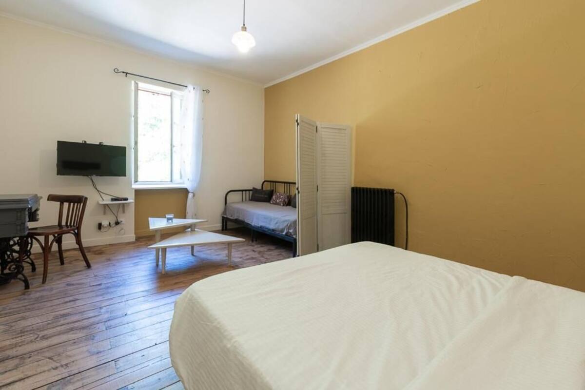 A room with a bed, a desk, a chair, a radiator, and a window.