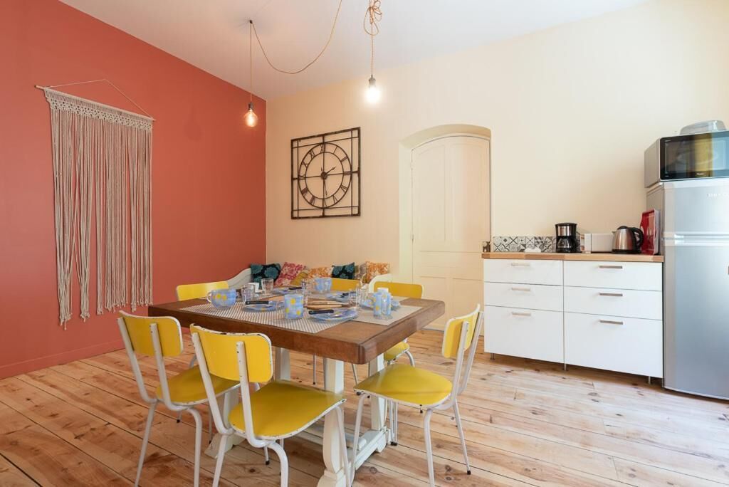 A dining area with a wooden table, yellow chairs, and a white cabinet with kitchen appliances.
