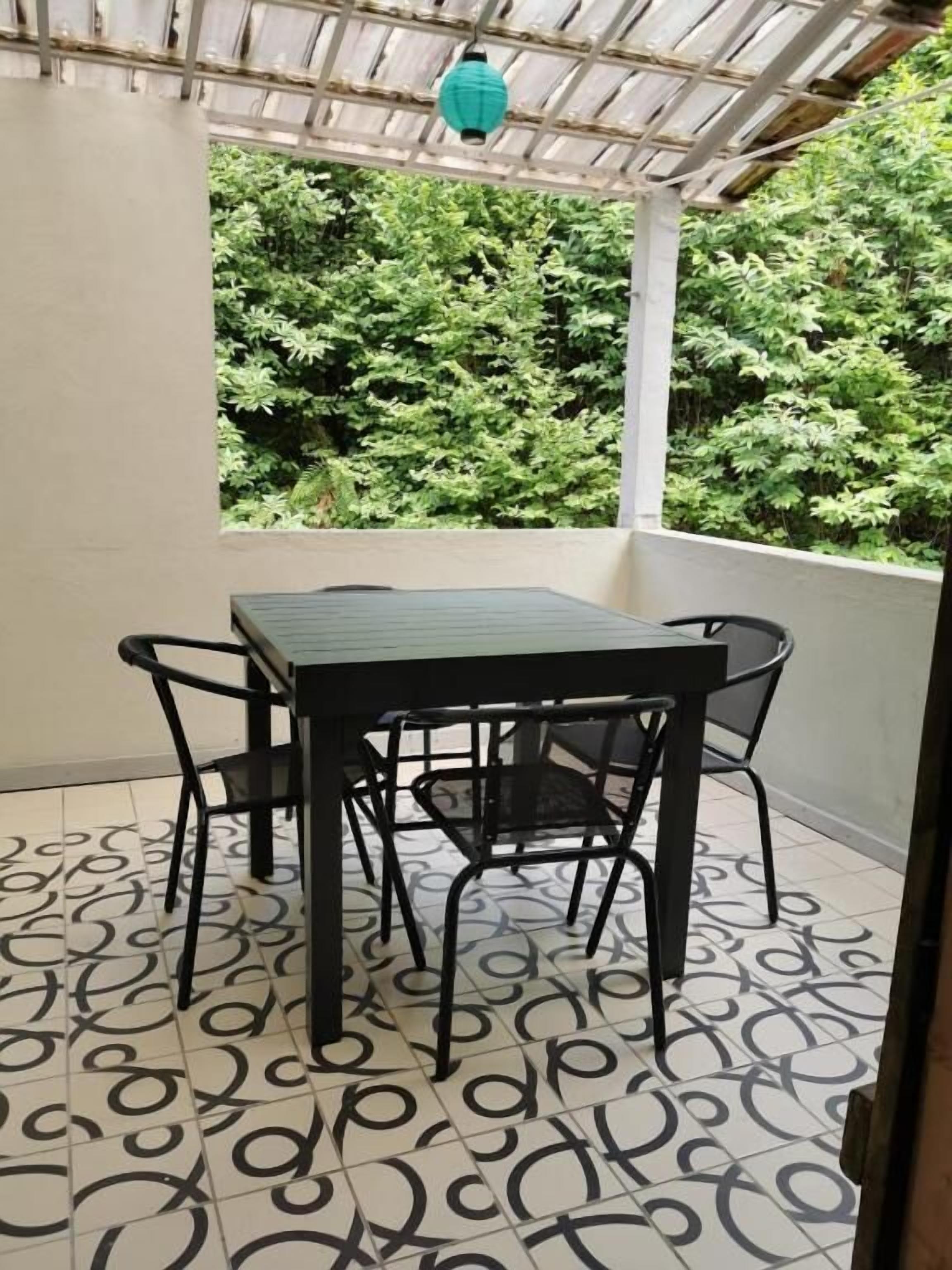 Een balkon met een tafel en stoelen, een vloer met patroon en uitzicht op groen.