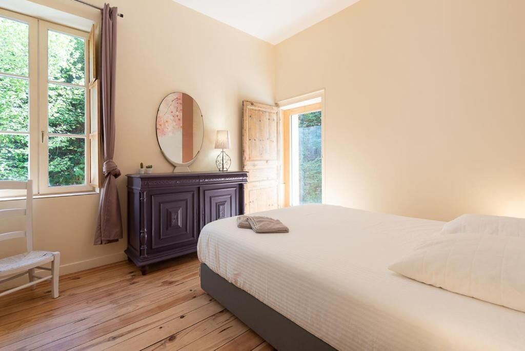 A bedroom with a bed, a dresser, a mirror, and a window with curtains.