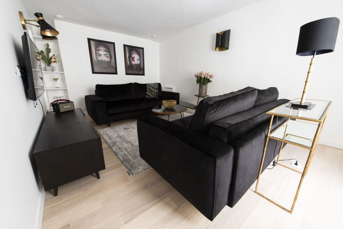 Een moderne woonkamer met een zwarte bank, een salontafel en een tv op een meubel.